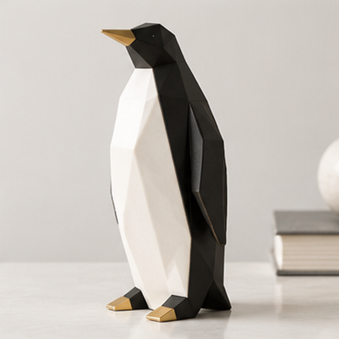 Black and white geometric penguin sculpture with gold-tone beak and feet on a light tabletop
